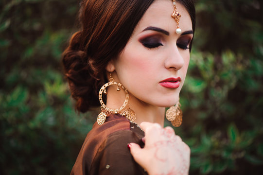 Beautiful young caucasian woman in traditional indian clothing sari with bridal makeup and jewelry and henna tattoo on hands