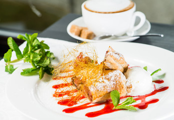 Delicious sweet strawberry strudel with candy sprinkles, mint and ice-cream in a white plate