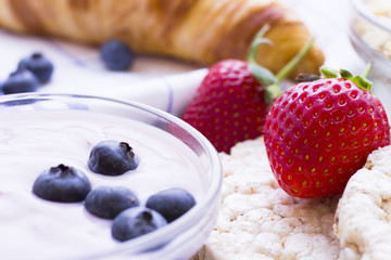 Romantic French or Rural Breakfast with youghurt, fresh berries, wheat breadcrisps and croissant, close up