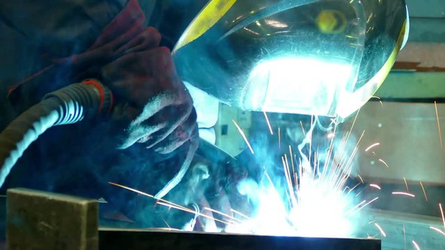 Welder Worker Performs Jump Welding / Worker welder performs arc-welding process of metal structures