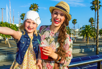 Naklejka premium matka i córka podróżujący z jasnoczerwonym napojem przy selfie