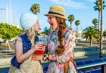 mother and daughter tourists showing tongues after drinking bright red beverage