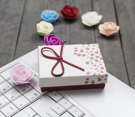 view of roses, white laptop and red gift box on background