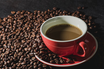 coffee in red cup and coffee beans are the background.