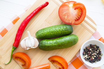 Preparing Healthy Food, Vegeterian, Vegan Concept. Cooking ingredients on a wooden cutting board :pepper, cucumbers, tomatoes, garlic, spices and herbs, top view