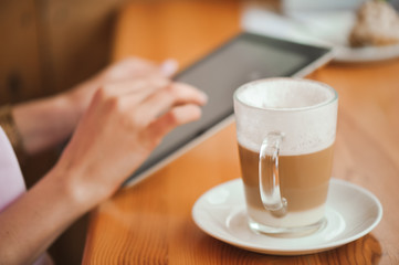 girl in cafe uses small mobile computer