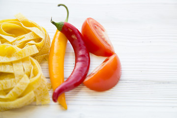 Preparing Healthy Food, Vegeterian, Vegan Concept. A close up of fetuccini nests, peppers and sliced tomatoes ,top view, flat lay. Space for a text or product display