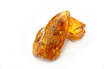 Two pieces of bright amber of different transparency red and yellow on a white background. Crystals of amber as a natural mineral for making jewelry. Sunstone. Macro photo  of amber with Inclusions