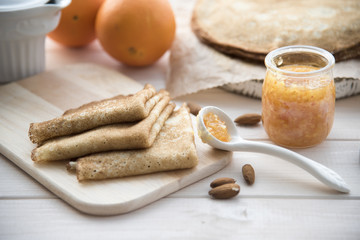 pancakes and orange jam on a light wooden background
