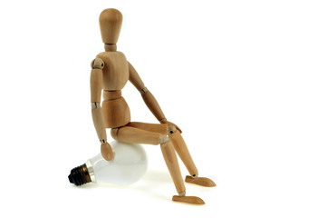 Mannequin en bois assis sur une ampoule électrique 