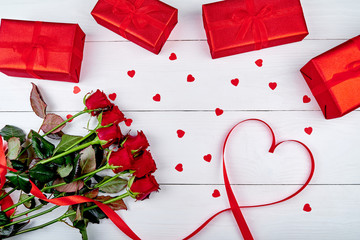 Valentines Day background with bouquet of red roses, gift boxes, ribbon shaped as heart, copy space. Greeting card mockup. Love concept. Top view, flat lay