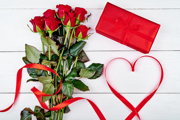 Valentines Day background with bouquet of red roses, gift box, ribbon shaped as heart, copy space. Greeting card mockup. Love concept. Top view, flat lay
