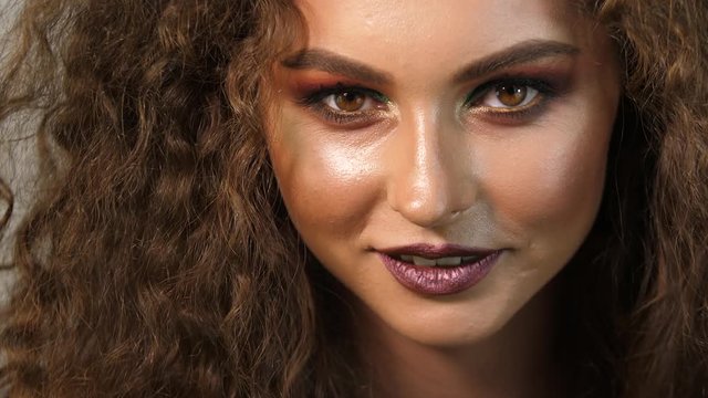 A beautiful girl with curls and excellent make-up, whose eyes are ready to punish any man.
