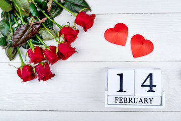 Valentines Day background with bouquet of red roses, two hearts and february 14 wooden calendar, copy space. Greeting card mockup. Love concept. Top view, flat lay