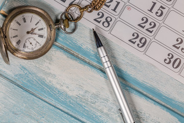 Siver Pocket Watch,Calendar and Pen On Wooden Background