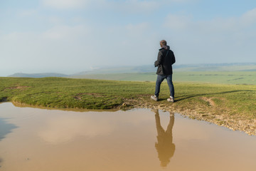 Naklejka na ściany i meble Male Backpacker walking alone in the wide nature England landscape 