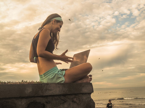 happy Digital Nomad girl with laptop on the beach