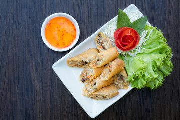 Veg. Spring Rolls on white dish on wooden table.Thai food and selective focus.