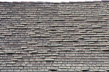 wood shingle roof in poor repair. Wood shingles are thin, tapered pieces of wood primarily used to cover roofs and walls of buildings to protect them from the weather. susceptible to fire and costly