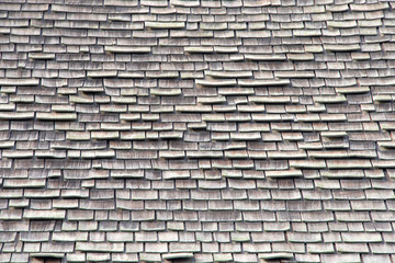 wood shingle roof in poor repair. Wood shingles are thin, tapered pieces of wood primarily used to cover roofs and walls of buildings to protect them from the weather. susceptible to fire and costly