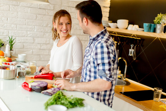 Young couple have fun in modern kitchen indoor while preparing vegetables food for lunch