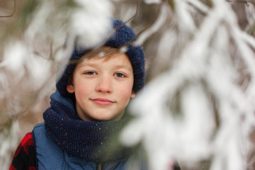 Closeup portrait of cute child boy in winter forest