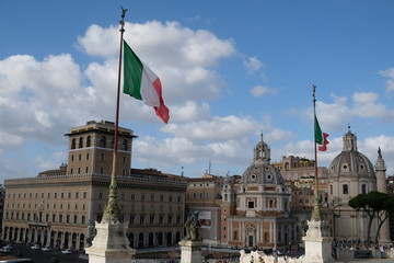 Obraz premium Italian flags in Piazza Venezia in Rome: Venezia Palace and Santa Maria di Loreto church on Trajan's Forum