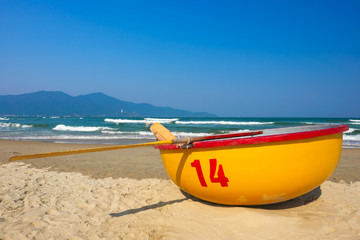 Yellow traditional circular fishing boat on a beach, Danang, Vietnam.