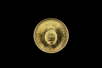 A super macro image of a gold argentinian ten centavo coin isolated on a black background