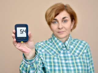 Woman showing glucose meter after measuring blood sugar. Selective focus.
