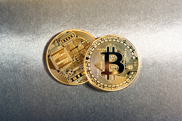Two gold Bitcoins on a reflective background