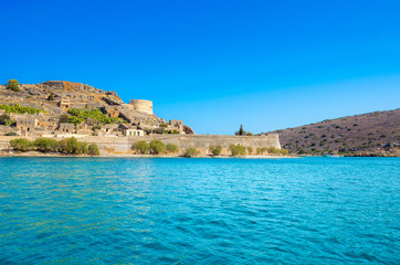 Fototapeta na wymiar View of the island of Spinalonga with calm sea. Here were isolated lepers, humans with the Hansen's desease, gulf of Elounda, Crete, Greece. 