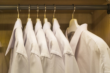 A row of symmetrically hung white mens shirts