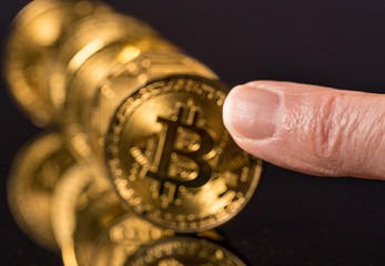 Bitcoins standing in a row like dominoes with finger