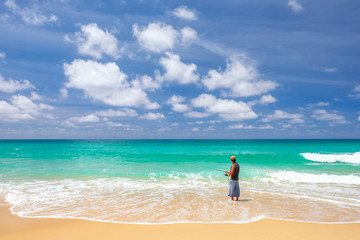Fisherman on the beach with sky and clouds. Surin beach, Phuket island, Thailand.