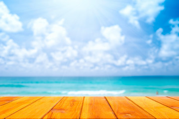 Wood plank with blurred sea background with bokeh and sun rays. Concept of beach in summer.
