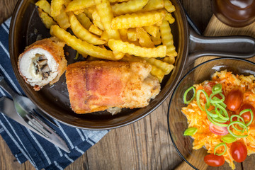 Fried chicken breast stuffed with mushrooms and cheese wrapped in ham served with fries and salad.