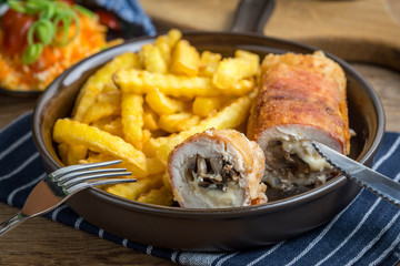 Fried chicken breast stuffed with mushrooms and cheese wrapped in ham served with fries and salad.