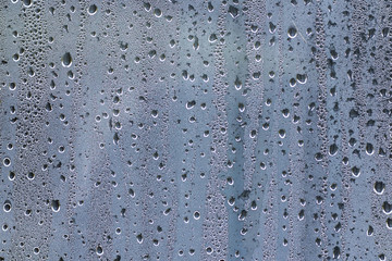 Drops of water slowly flowing down the glass