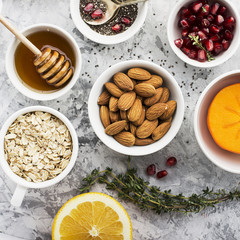 Ingredients for a healthy breakfast, nuts, oatmeal, honey, berries, fruits, blueberry, orange, pomegranate seeds, almonds, walnuts The concept of natural organic food in season. Top view