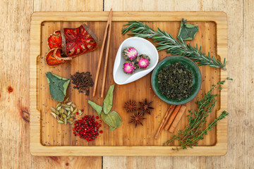 Chinese Oolong jasmine tea (Moli Yu Lun Tao) in a white bowl and chinese Oolong green tea (Tie Guan Yin) in a green bowl. On a wooden board scattered a lot of ingredients for tea.