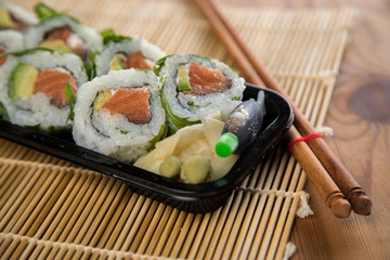 Lachs Avocado Rucola Inside Out Sushi in Lieferdienst Verpackung mit Stäbchen