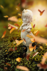 Obraz na płótnie Canvas Sculpture of little girl with autumn leaves, background for Valentine's day. Selective focus and color toned.