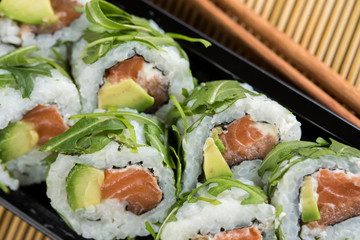 Lachs Avocado Rucola Inside Out Sushi in Lieferdienst Verpackung mit Stäbchen