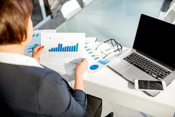 Senior woman working with paper charts and analityc graphics. Close-up view on the hands and documents