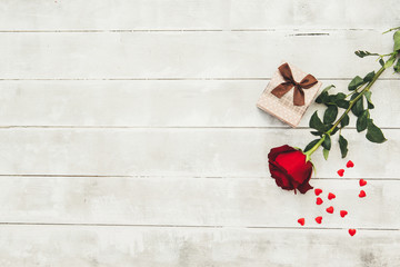 Red rose and gift box on wooden table. Valentines Day background