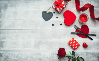 Valentine's day table setting with  fork, knife, red hearts, ribbon and roses. Valentines day background or first date