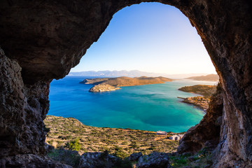 Fototapeta premium Panoramic view of the gulf of Elounda with Spinalonga island. View from the mountain through a cave, Crete, Greece.