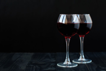 Two glasses of red wine on a black background