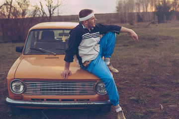 guy in the nineties lies on the hood of an old car